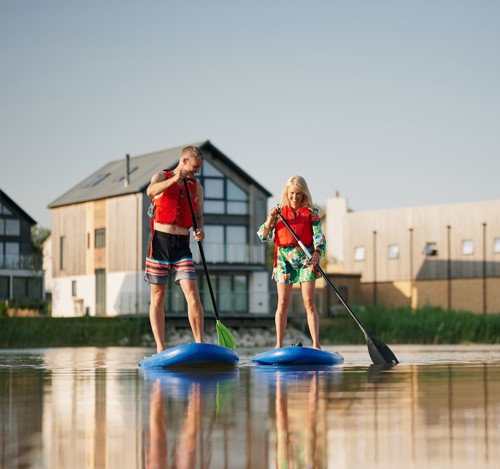 a man and a woman paddleboarding on a lake