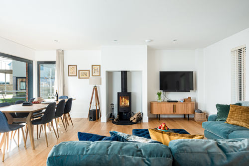 A large reception room with sofa, dining table and log burner