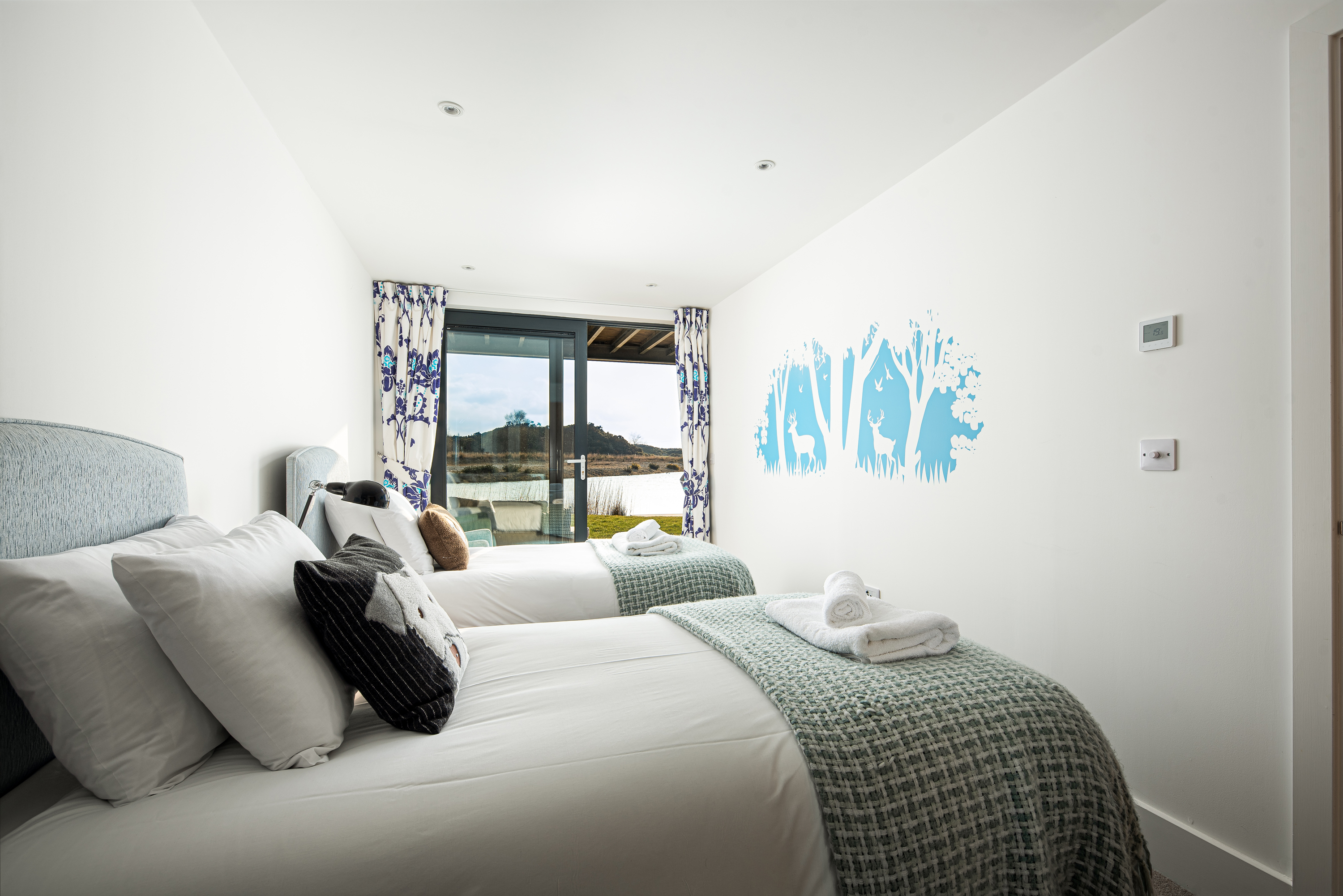 Twin room with stencil on wall of deer and trees