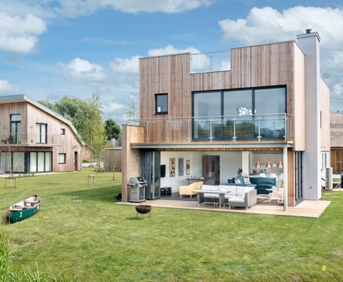 A square wooden holiday home surrounded by lush grass