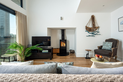 The inside of a modern sitting room with a log burner and armchair