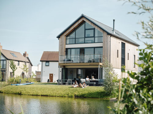 The outside of a large holiday home by a lake